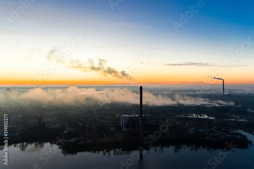 Power plant smokestacks at sunrise near the lake. Environmental pollution.