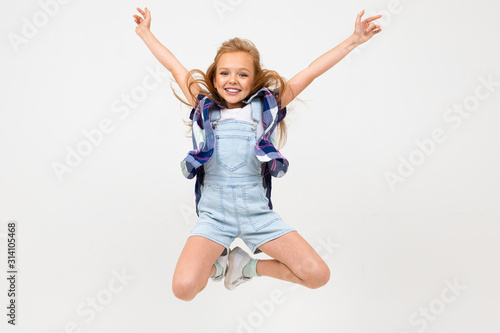 young girl jumping in casual clothes on a light blue studio background