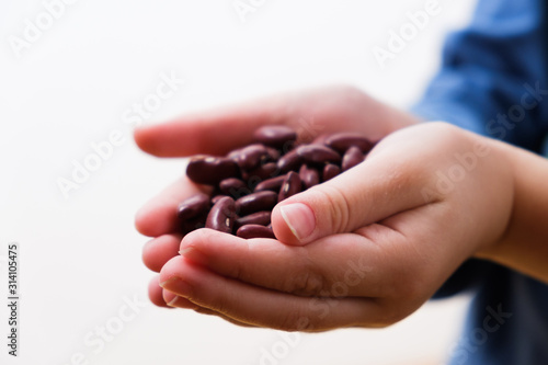 Small hungry child gets food donate help a volunteer, hands full of beans