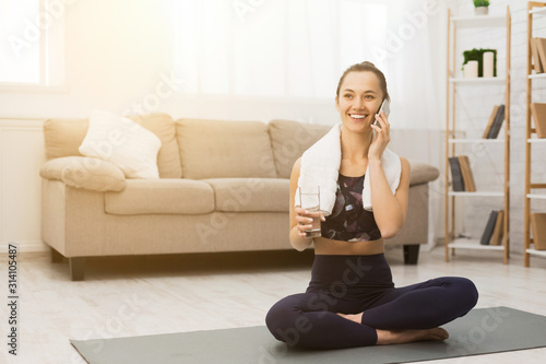 Happy woman talking on phone after training at home