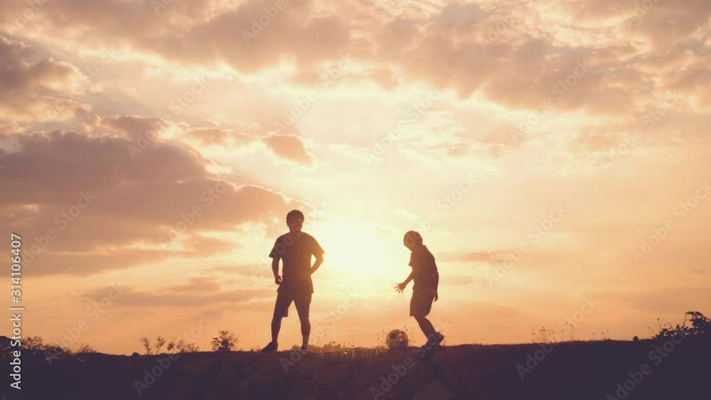 Father and son Soccer players in the park at the sunset time.Concept of friendly and happy family. Father and son Soccer players in the park at the sunset time.Concept of friendly and happy family.