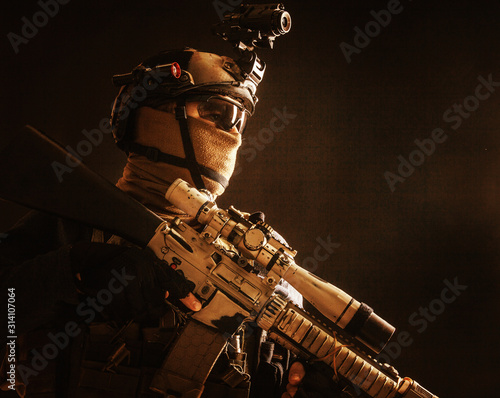 Shoulder portrait of army elite troops sniper, anti-terrorist tactical team marksman wearing helmet with thermal imager, hiding face behind mask, armed rifle with optical scope, studio shoot on black photo