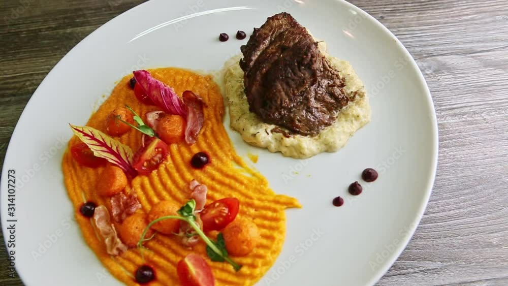 big piece of grilled meat with trendy decorated garnish rotates on plate big piece of grilled meat with trendy decorated garnish rotates on plate