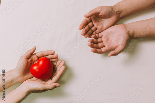 Hands couple holding red hearts, love, valentine, health care, donation and family insurance concepts, World Heart Day, prayer together.