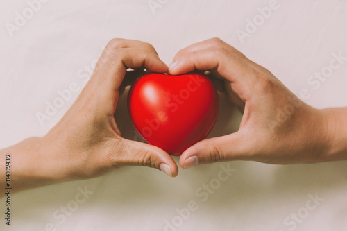 Fototapeta Naklejka Na Ścianę i Meble -  Hands couple holding red hearts, love, valentine, health care, donation and family insurance concepts, World Heart Day, prayer together.