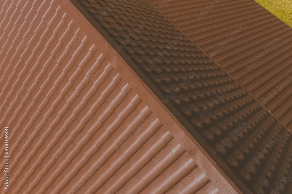 Brown metal tile on the roof of the house. Corrugated metal roof Brown metal tile on the roof of the house. Corrugated metal roof