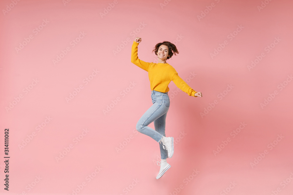 Joyful young brunette woman girl in yellow sweater posing isolated on pastel pink wall background. People lifestyle concept. Mock up copy space. Having fun fooling around jumping doing winner gesture. Joyful young brunette woman girl in yellow sweater posing isolated on pastel pink wall background. People lifestyle concept. Mock up copy space. Having fun fooling around jumping doing winner gesture.