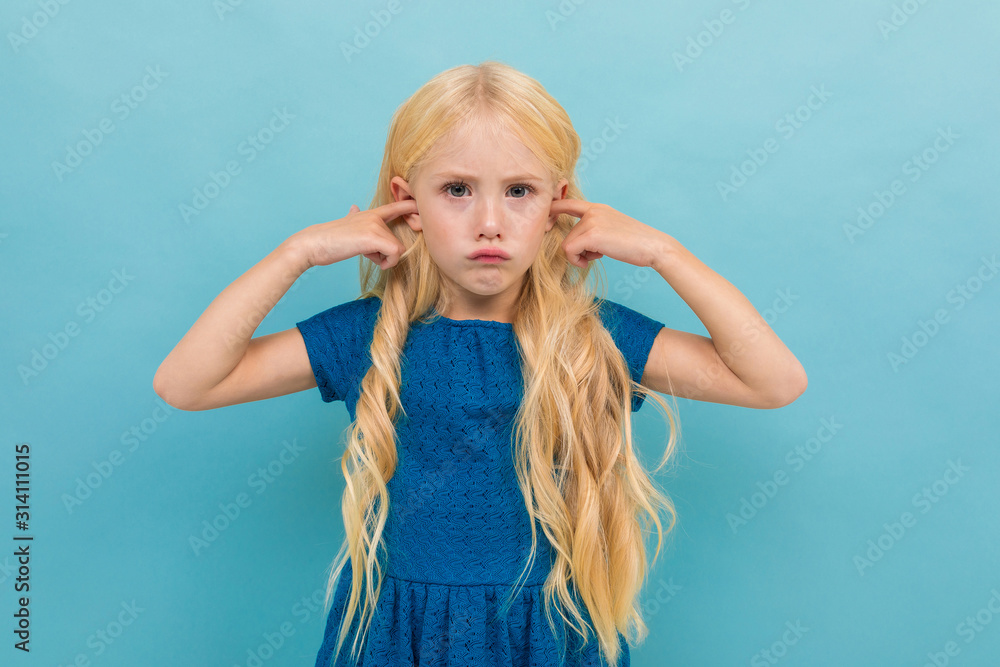 Portrait of little caucasian girl in blue dress with long blonde hair hear nothing isolated on blue background
