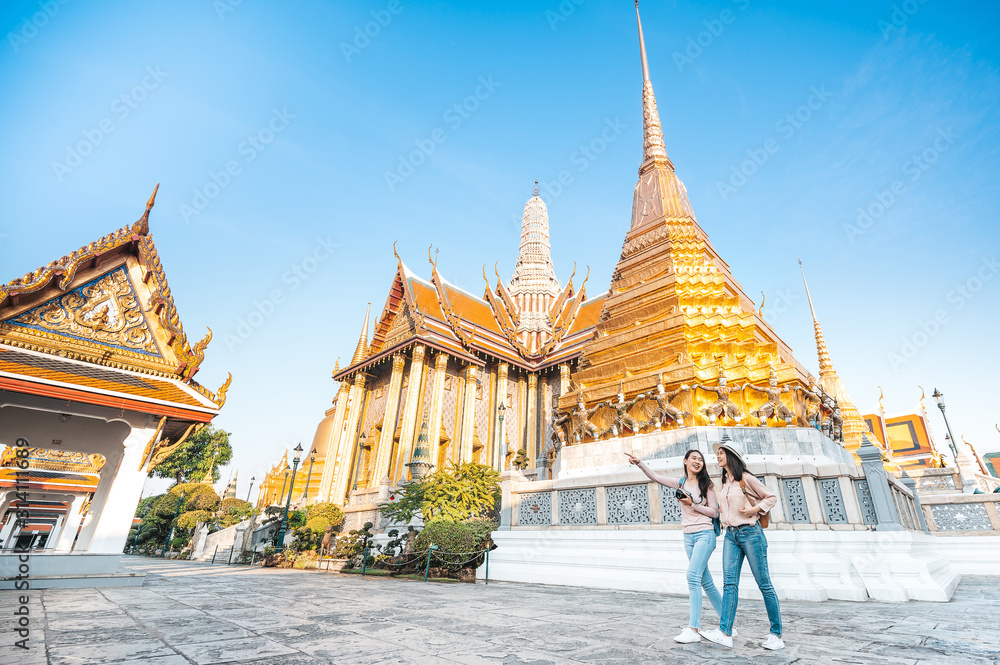 Naklejka premium women friends enjoy sightseeing while travel in temple of the emerald buddha in Thailand