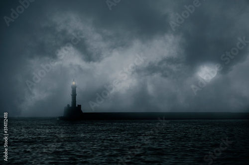 Lonely lighthouse on stormy sea against dark clouds