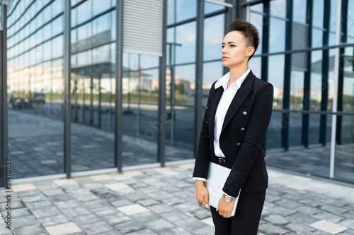 girl in classic style stands with papers at the facade of a modern building of a business center