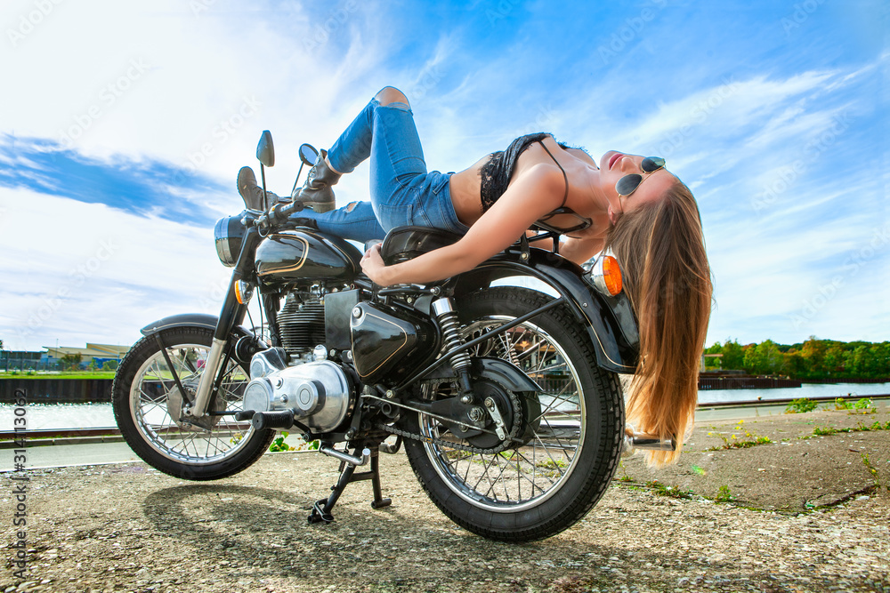 Obraz premium An attractive girl on a motorbike posing outside
