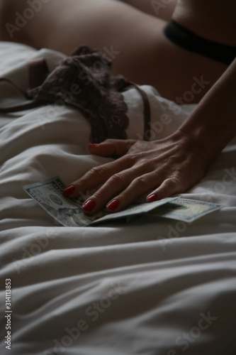 Money and young woman in hotel room as a symbol of  prostitution, modern slav...