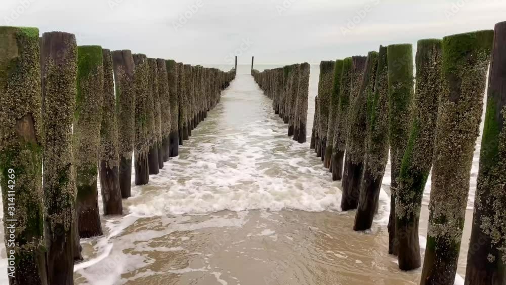 4K Shot of waves from the North Sea moving through beach poles, Vlissingen, Netherlands, Zeeland. 4K Shot of waves from the North Sea moving through beach poles, Vlissingen, Netherlands, Zeeland.