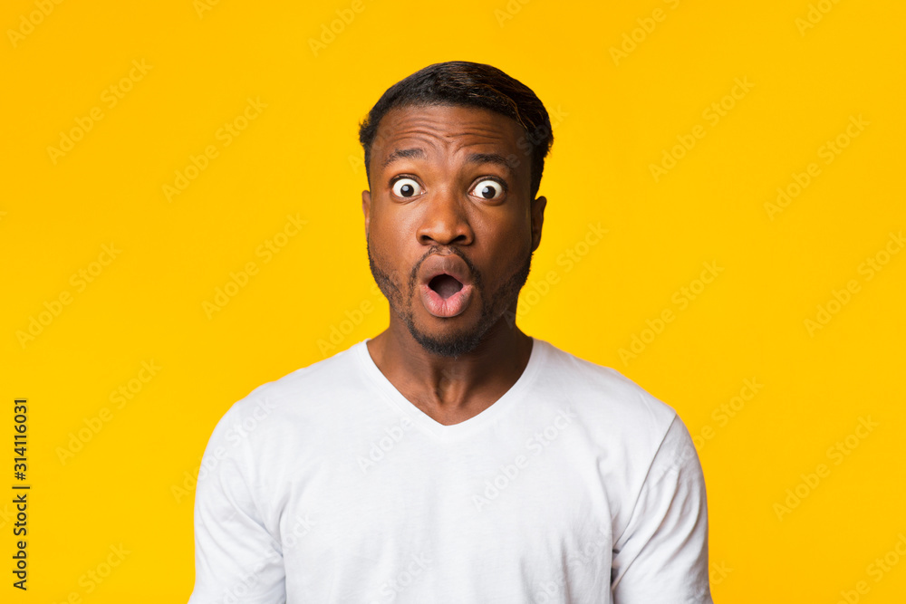 Afro Guy Looking At Camera In Surprise Over Yellow Background Afro Guy Looking At Camera In Surprise Over Yellow Background