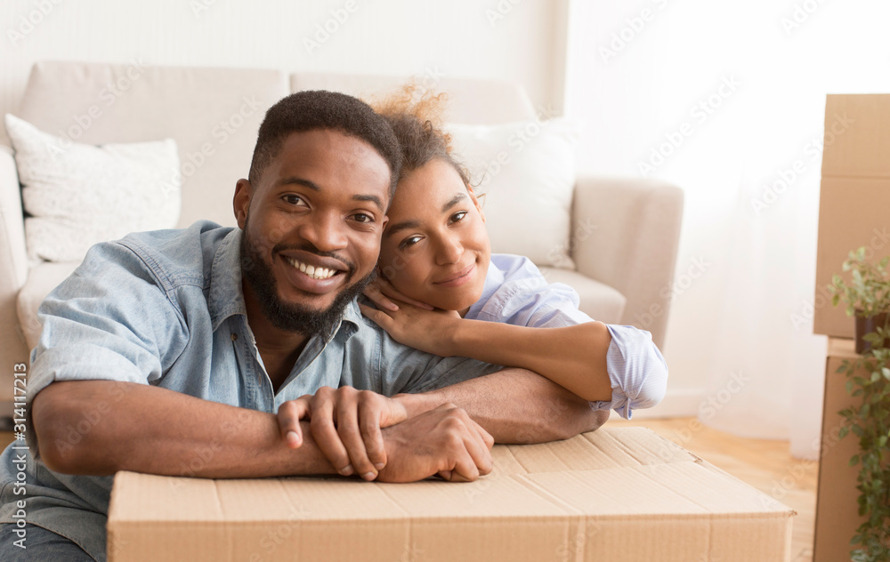 Happy Couple Hugging Sitting Among Unpacked Boxes In New Home Happy Couple Hugging Sitting Among Unpacked Boxes In New Home