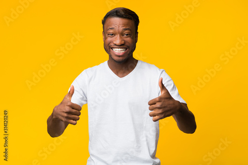 Millennial Guy Gesturing Thumbs Up With Both Hands In Studio
