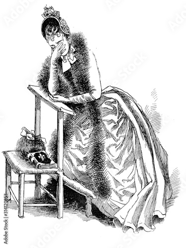 French portrait and caricature: Young broken-hearted woman fancy dressed with fur and fashionable hat cries praying on a kneeler in church alone photo