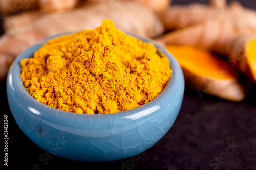Food and drink, diet nutrition, health care concept. Raw organic orange turmeric root and powder, curcuma longa on a grunge cooking table. Indian oriental low cholesterol spices