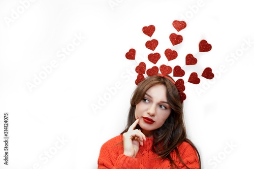 Beautiful Girl female with red plump lips, red sweater and crown of shiny glitter hearts isolated on white backdrop. Concept for valentine's day. Festive greeting card with copy space. Selective focus