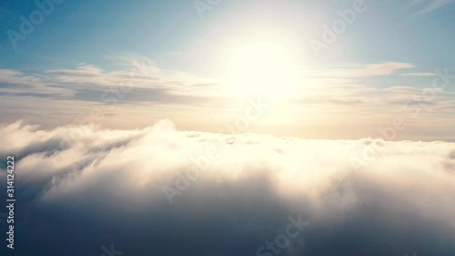 Aerial view up from the clouds to the sky in motion. Aerial view white clouds in blue sky during sunrise or sunset. Aerial top view cloudscape. Texture of clouds. Panoramic view. Clouds in motion