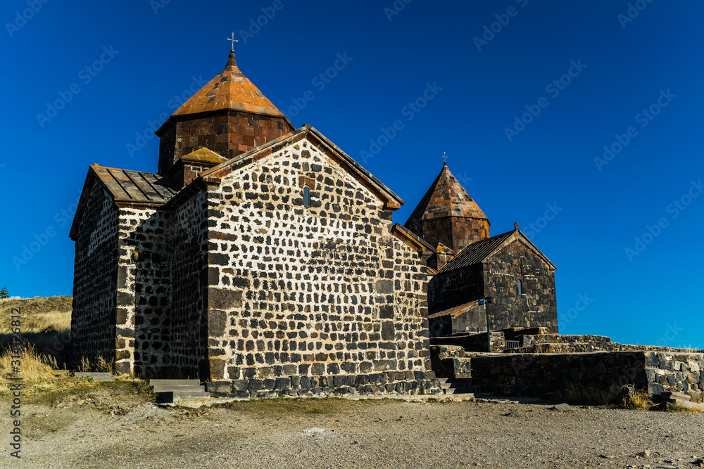 Fototapeta premium Old orthodox monastery Sevanavank located on a peninsula at the northwestern shore of Lake Sevan in Armenia. View during autumn sunny day 