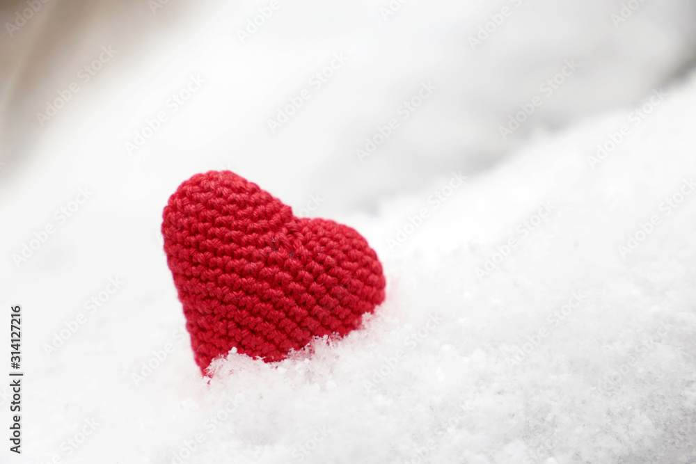 Fototapeta premium Valentine's day, red knitted heart in the snow. Background for romantic event, celebration or winter weather