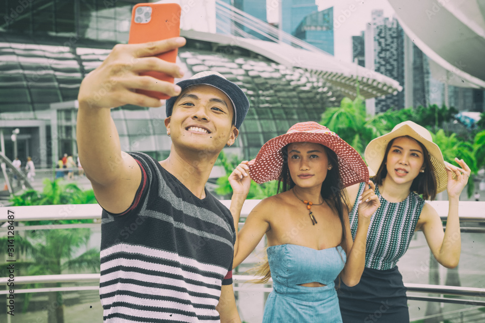 Three asian friends walking along the city taking selfies. Tourism and holiday concept