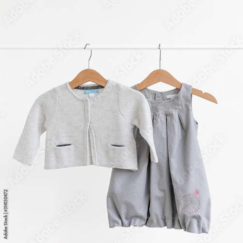 Female child's (baby-girl) dress and knitted jacket hanging on sholders on a white background/ Summer and spring wardrobe/ Children's clothes/ Baby wear set