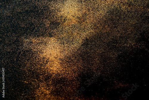 Black background with golden sparkles. Blurred effect. Concept for festive background or for project