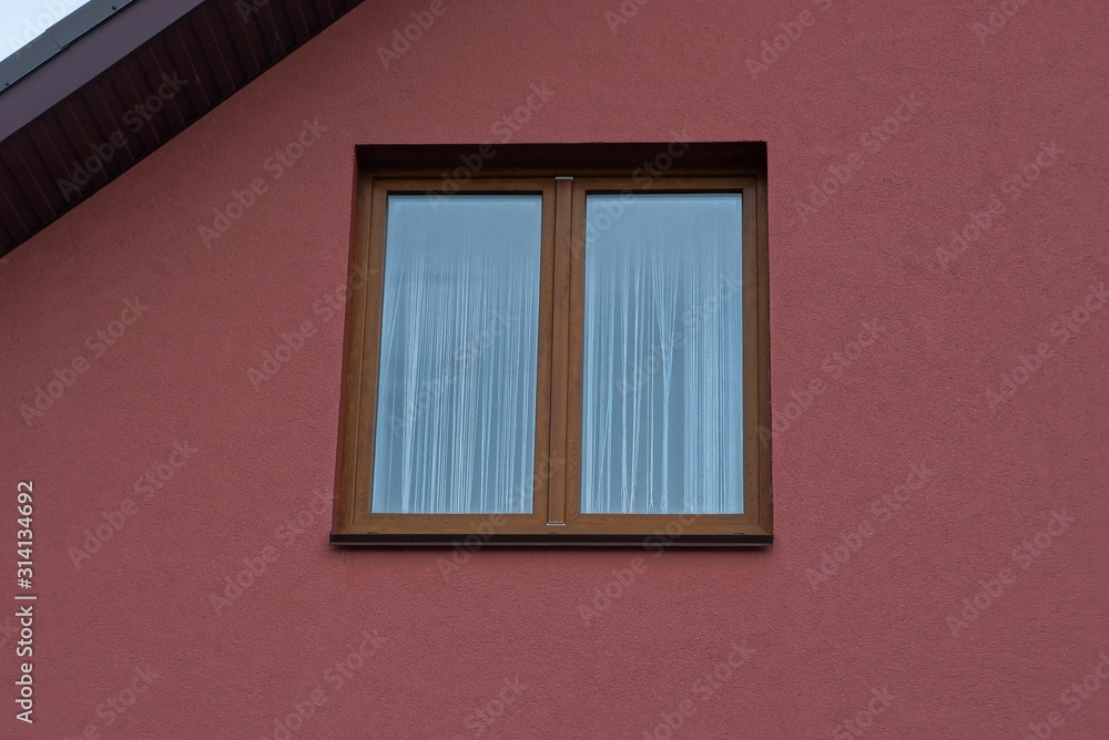 one brown large window on the plastered red wall of a private house on the street one brown large window on the plastered red wall of a private house on the street