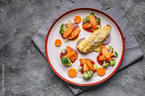 Top view fillet of sea bass with vegetables. Baked fish, cauliflower and carrots on a big plate. Copy space