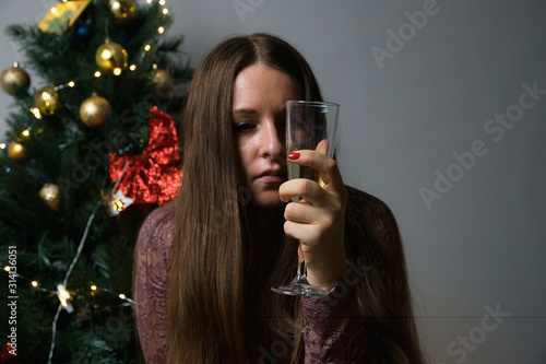 Girl with a glass of champagne near the Christmas tree. New year's photo shoot.