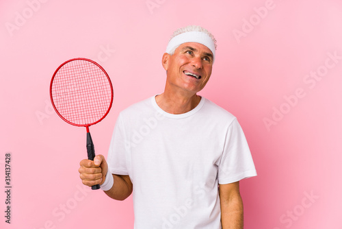 Middle aged man playing badminton isolated dreaming of achieving goals and purposes © Asier