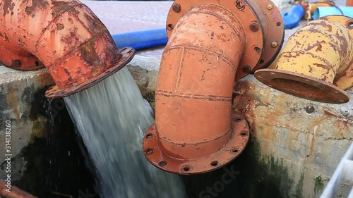Water Splash flowing from rusted metal culvert drain pipe opening 