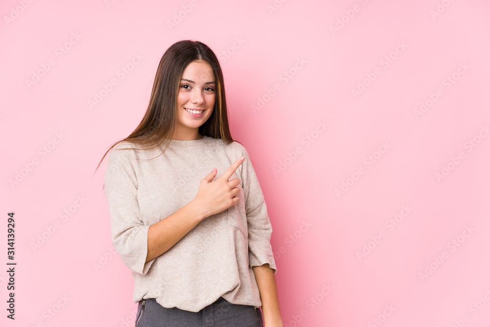 Fototapeta premium Young caucasian woman posing isolated smiling and pointing aside, showing something at blank space.