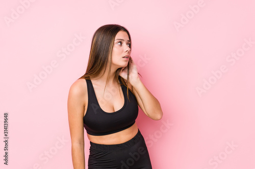 Young fitness caucasian woman isolated trying to listening a gossip.