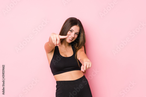 Young fitness caucasian woman isolated cheerful smiles pointing to front.