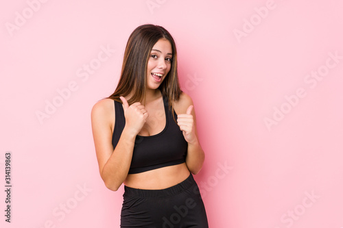 Young fitness caucasian woman isolated raising both thumbs up, smiling and confident. © Asier
