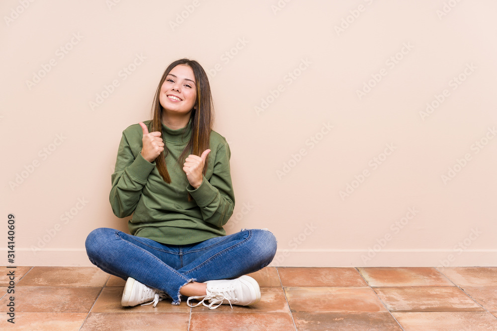 Young caucasian woman sitting on the floor isolated raising both thumbs up, smiling and confident. Young caucasian woman sitting on the floor isolated raising both thumbs up, smiling and confident.