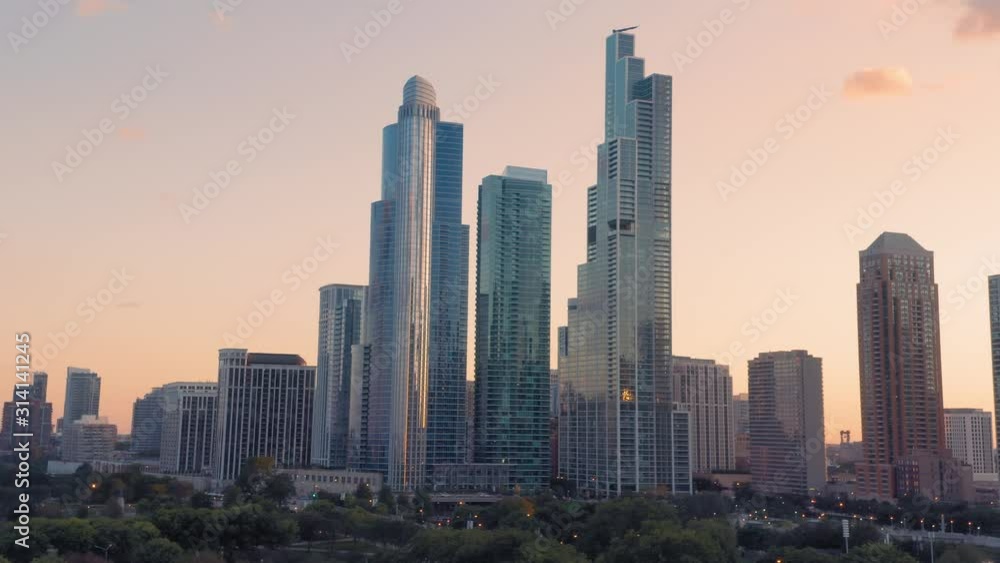 Aerial: Tourists at Buckingham Fountain in Grant Park at sunset. In the background is the Chicago City Skyline. Aerial: Tourists at Buckingham Fountain in Grant Park at sunset. In the background is the Chicago City Skyline.