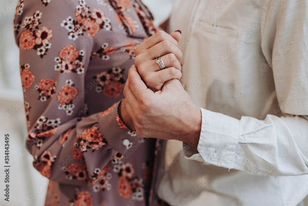 A romantic couple holding hands with wedding rings. A romantic couple holding hands with wedding rings.
