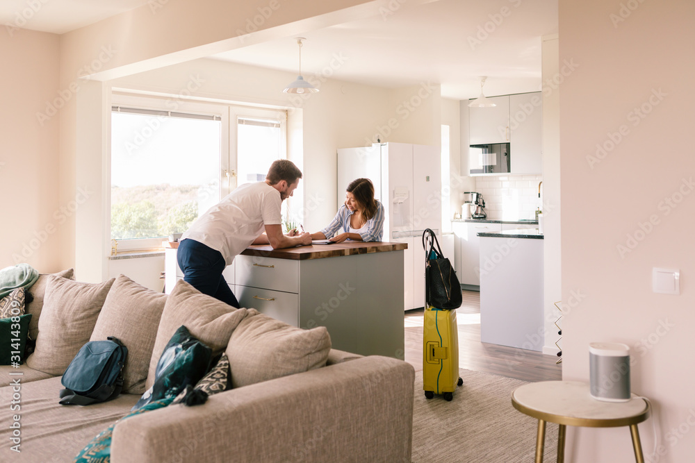 Landlord looking at tenant filling form in house rental Landlord looking at tenant filling form in house rental