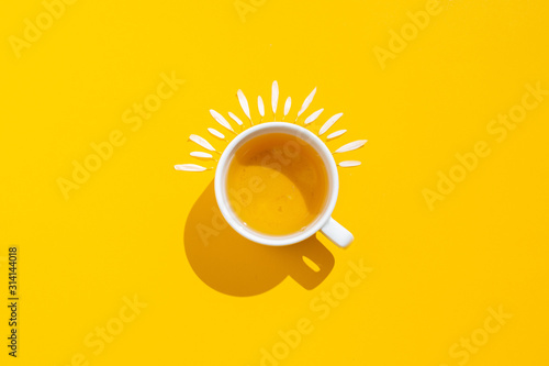 Hot drink, cup of tea with chamomile and lemon on a yellow background photo