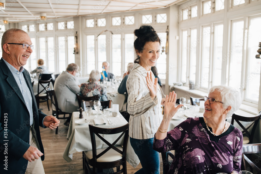 Senior friends giving high-five in restaurant Senior friends giving high-five in restaurant
