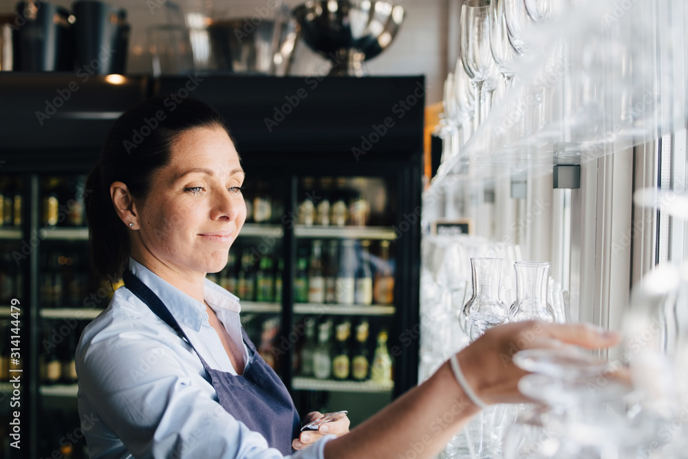 Smiling woman arranging wineglasses in restaurant Smiling woman arranging wineglasses in restaurant