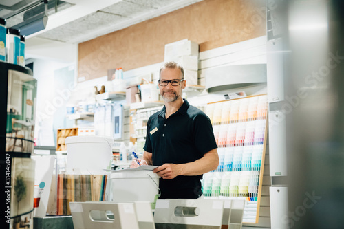 Portrait of smiling employee working in hardware store photo