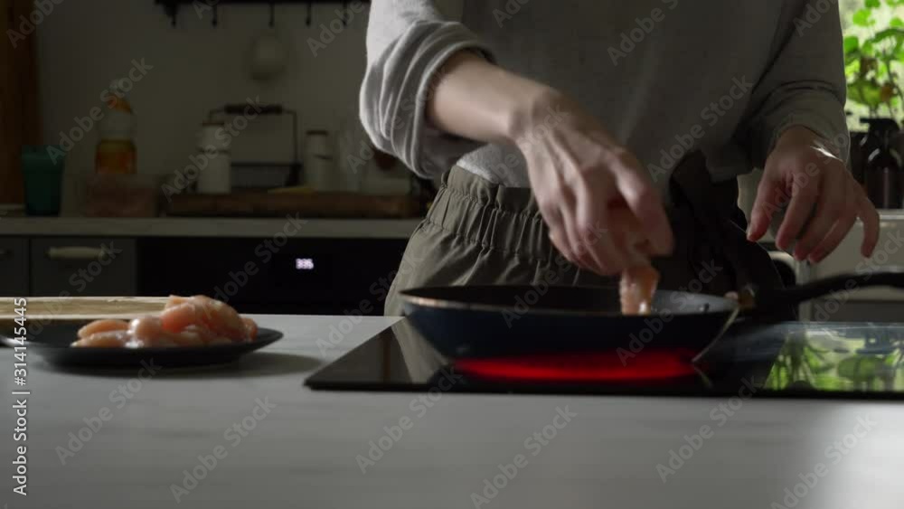woman roasts a chicken in a frying pan in her kitchen woman roasts a chicken in a frying pan in her kitchen