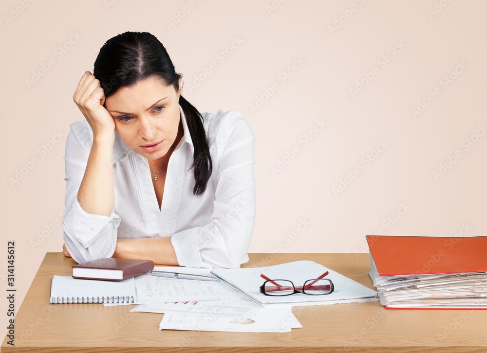Young businesswoman hid behind with stack of papers on wooden table in room Young businesswoman hid behind with stack of papers on wooden table in room