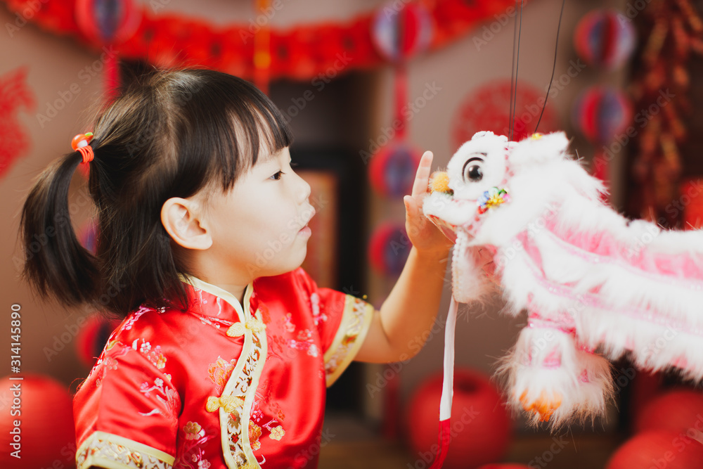 Φωτογραφία Chinese toddler girl with traditional dressing up and holding dancing lion with